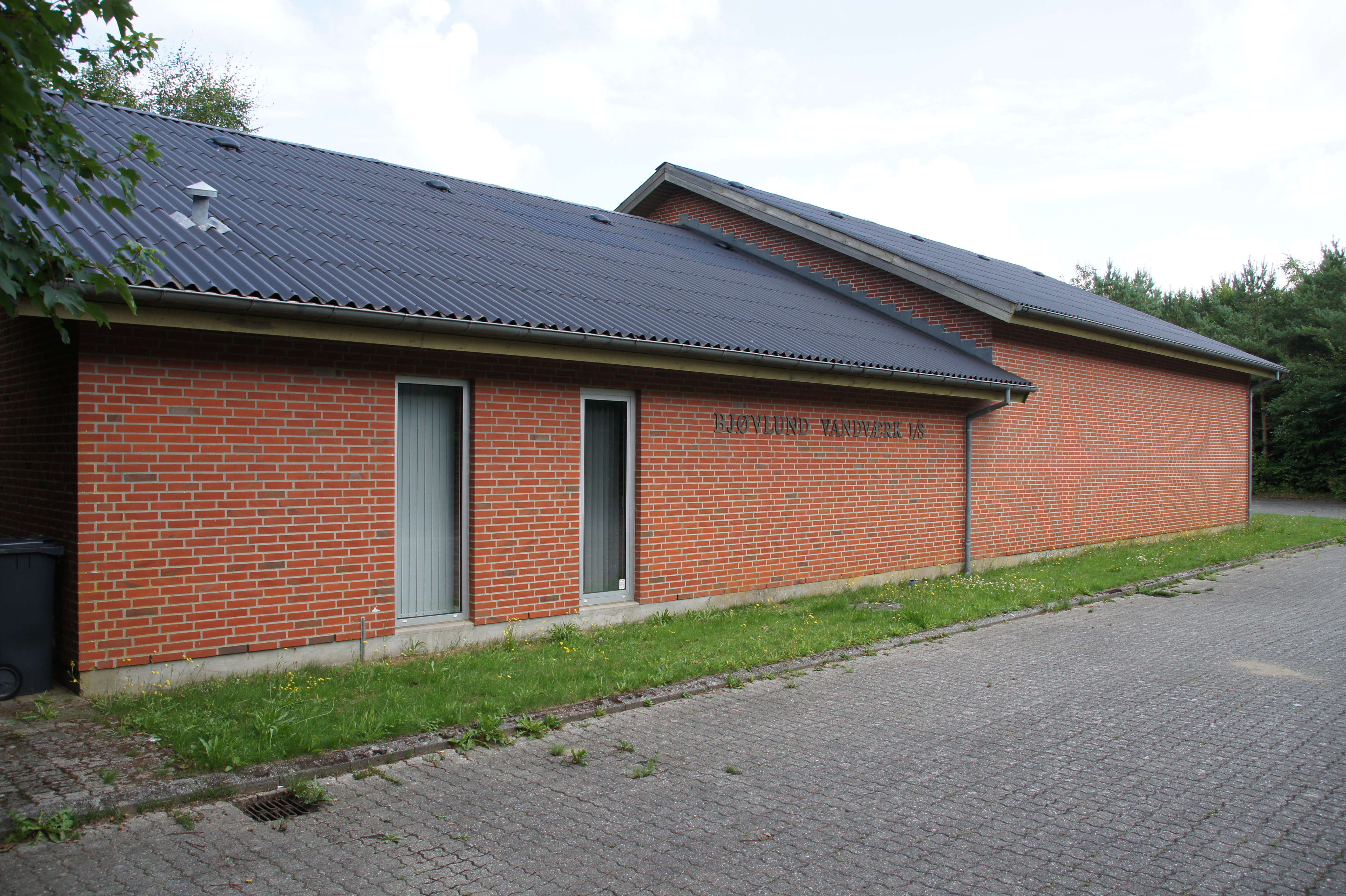 Bjøvlund Vandværk - Rød bygning med mørkt tag ved grusvej